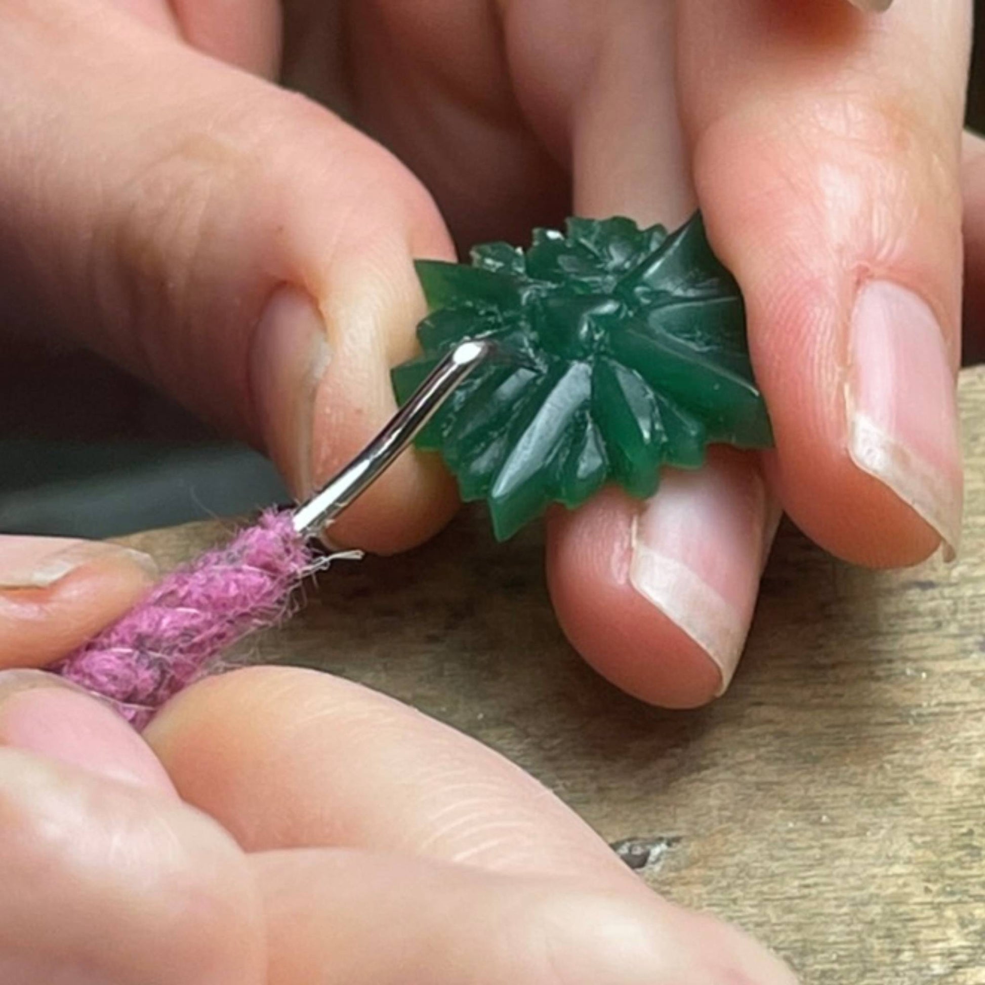 Close-up of hands carving green wax with a wax carver.