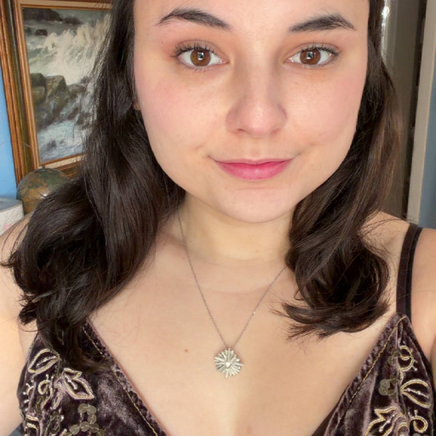 Woman with wavy hair wearing a necklace in an indoor setting